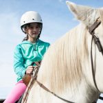 young girl riding a white horse