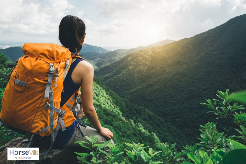 lady hiking in a mountain with bright orange bag