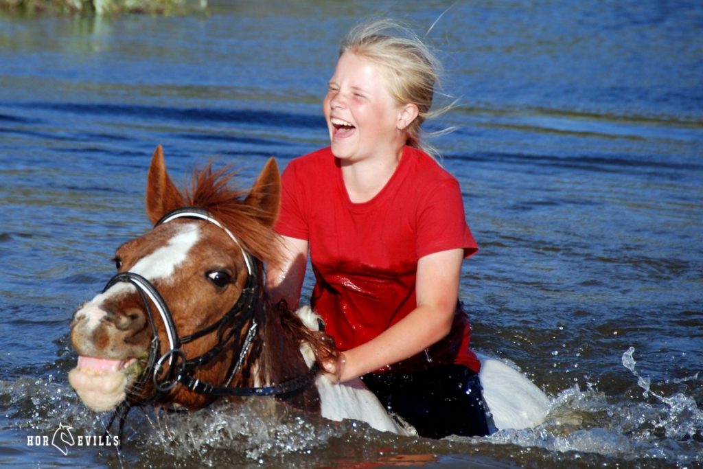 a lady riding a horse while its swimming